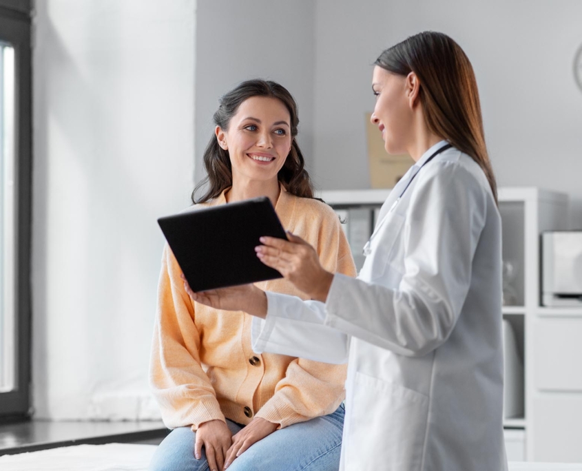 Side view of a healthcare professional speaking with a patient while holding a smart tablet